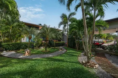 a yard with palm trees and a house at Aroha Villa with Private Pool Near Nai Harn Beach in Rawai Beach