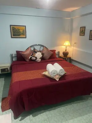a bedroom with a red bed with towels on it at Rungtawan Hostel in Karon Beach