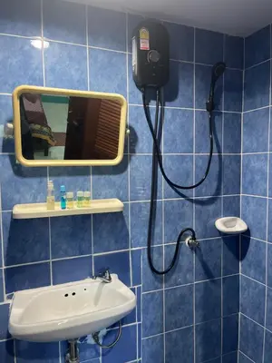 a blue tiled bathroom with a mirror and a sink at Rungtawan Hostel in Karon Beach