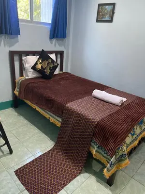 a bed with two pillows and a blanket on it at Rungtawan Hostel in Karon Beach