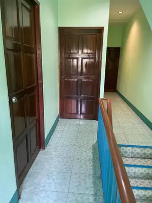 a hallway with two wooden doors and a staircase at Rungtawan Hostel in Karon Beach