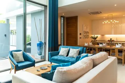 a living room with blue furniture and a kitchen at Luxury Teak 4BR Private Pool Villa in Bang Tao in Laguna Phuket