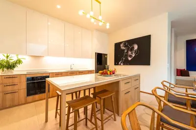 a kitchen with wooden cabinets and a island with chairs at Luxury Teak 4BR Private Pool Villa in Bang Tao in Laguna Phuket