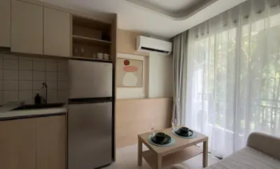 a kitchen with a refrigerator and a table and a window at New apartment at Fantasea Kamala by Lofty in Kamala Beach