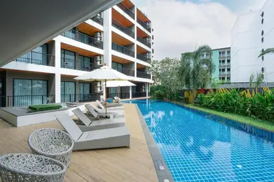 a swimming pool with chairs and an umbrella next to a building at Modern Studio @ Kata Beach in Ban Karon