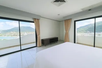 a bedroom with a white bed and large windows at Patong Beachfront Tower 30 Floor Penthouse in Patong Beach