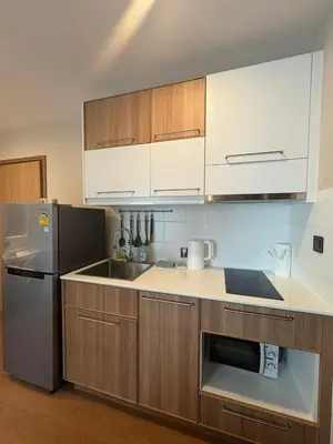 a kitchen with wooden cabinets and a stainless steel refrigerator at Comfortable Relax at Rawai Title in Ban Saiyuan (1)