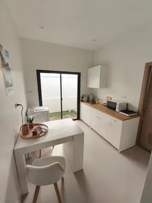 a white kitchen with a table and a chair at PS Guesthouse in Kathu