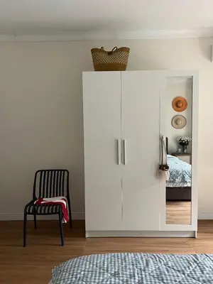 a white cabinet in a bedroom with a chair at Roomy renovated Apartments in Phuket in Ban Sam Kong