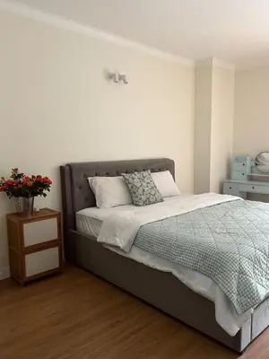 a bedroom with a bed and a night stand with flowers at Roomy renovated Apartments in Phuket in Ban Sam Kong