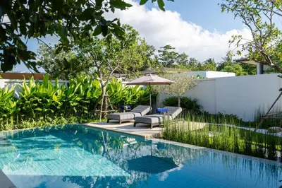 a swimming pool with two lounge chairs and an umbrella at Villa Kaya, 3BR contemporary pool villa in Phuket