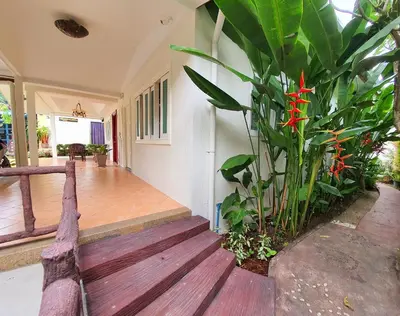 a porch with a plant and a wooden deck at Muchshima House in Bang Tao Beach