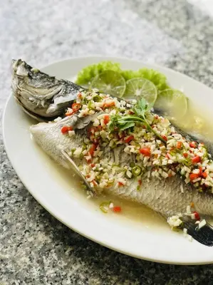 a plate of fish with rice and vegetables on it at Muchshima House in Bang Tao Beach