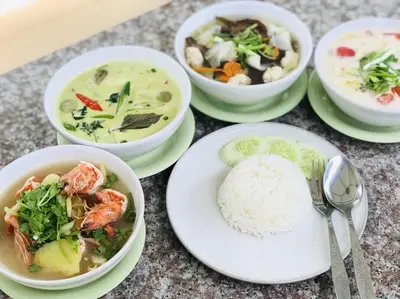 a table topped with bowls of soup and rice at Muchshima House in Bang Tao Beach