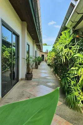 a hallway of a building with plants and a pathway at Muchshima House in Bang Tao Beach
