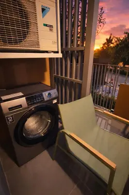 a chair and a washing machine on a balcony at New 1BR Condo, walk to Bang Tao Beach in Laguna Phuket