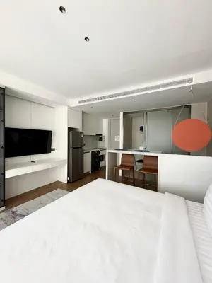 a bedroom with a large white bed and a kitchen at Beach Resort along coastline of Layan beach in Layan Beach