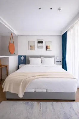 a bedroom with a large white bed with blue curtains at Beach Resort along coastline of Layan beach in Layan Beach