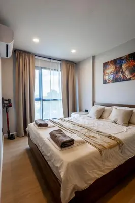 a large bed in a bedroom with a large window at Modern apartment in the heart of Bangtao in Ban Thalat Choeng Thale