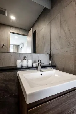a bathroom with a white sink and a mirror at Modern apartment in the heart of Bangtao in Ban Thalat Choeng Thale