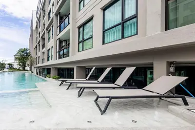 a row of lounge chairs sitting next to a building at Modern apartment in the heart of Bangtao in Ban Thalat Choeng Thale