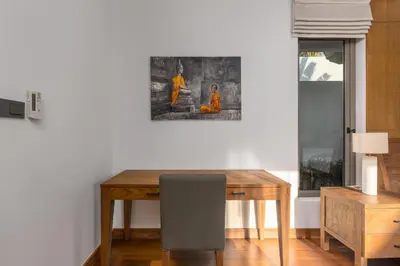 a dining room with a wooden table and a picture on the wall at Modern 3BR Villa Kaimana with Private Pool in Ban Phru Champa