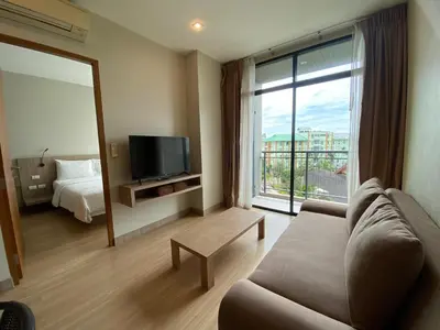 a living room with a couch and a large window at Apartments with access to Rama IX Park in Ban Lo Long
