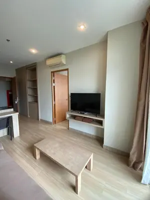 a living room with a coffee table and a television at Apartments with access to Rama IX Park in Ban Lo Long