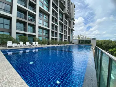 a swimming pool in front of a building at Apartments with access to Rama IX Park in Ban Lo Long