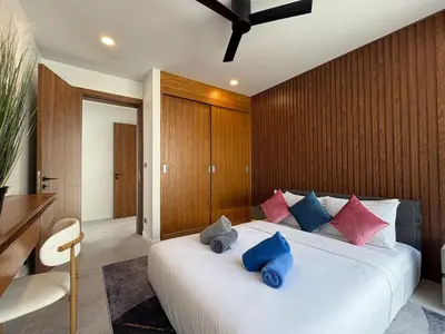 a bedroom with a white bed with blue and pink pillows at Newly built private Quinta Lane 4br pool villa in Ban Saiyuan (1)