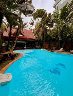 a large blue swimming pool with palm trees and a building at Bright Sun Apartment with Pools in Rawai Beach