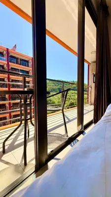 a bedroom with a bed and a view of a balcony at Bright Sun Apartment with Pools in Rawai Beach