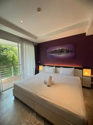 a bedroom with a large white bed with a purple wall at Phuket Rawai beachfront by Tris in Nai Harn Beach