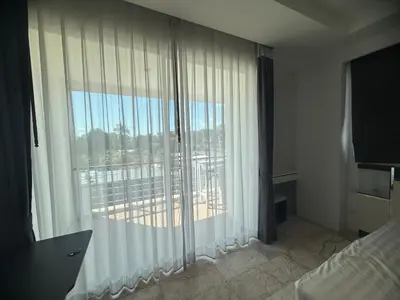 a bedroom with a large window with white curtains at Phuket Rawai beachfront by Tris in Nai Harn Beach
