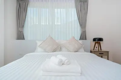 a bedroom with a white bed with two towels at Espuma Patong pool villa in Patong Beach