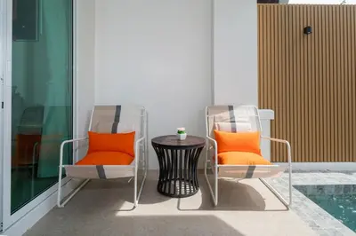 two chairs with orange pillows sitting next to a table at Suite dream villa Bangla Patong sleep 8 in Patong Beach
