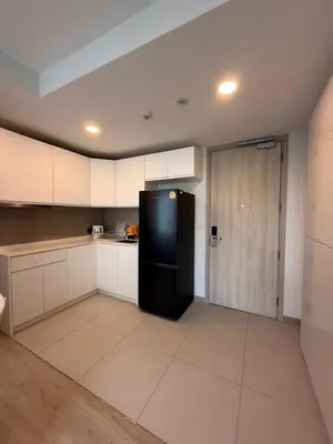 a kitchen with white cabinets and a black refrigerator at Sky Park Family Comfort in Laguna Phuket