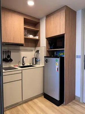 a small kitchen with a refrigerator and wooden cabinets at SkyPark Laguna, 1 Bedroom Apartment in Phuket