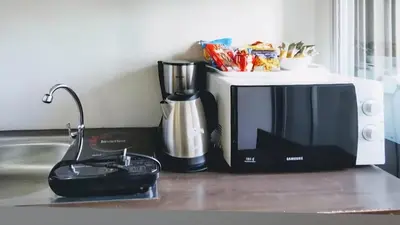 a kitchen counter with a microwave and a coffee maker at studio room dami in Kathu
