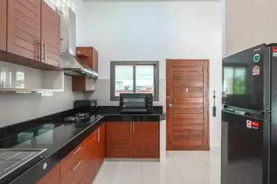 a kitchen with wooden cabinets and a black counter top at Orchid Pool Villa 8 Rawai in Rawai Beach