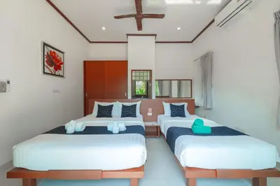 two beds in a room with white walls at Orchid Pool Villa 8 Rawai in Rawai Beach
