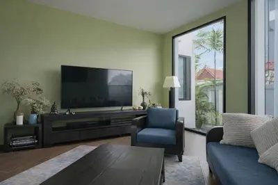 a living room with a television and a blue chair at Private Pool Villa Baan Bua in Phuket Town