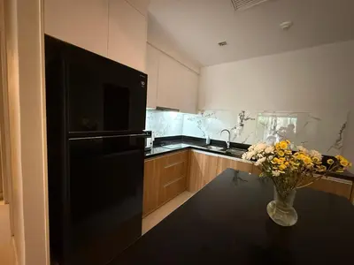 a kitchen with a black refrigerator and a vase of flowers on a table at Luxury 112 m 2BR, Direct Pool Access, 1st Line, Klong Muang Beach in Ban Ko Kwang