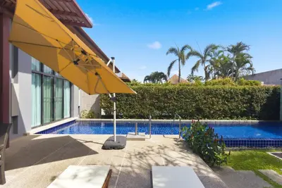 a yellow umbrella sitting next to a swimming pool at Onyx Villa by Beringela in Rawai Beach
