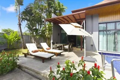 a patio with a table and chairs and an umbrella at Onyx Villa by Beringela in Rawai Beach