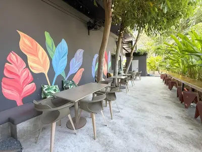 a row of tables and chairs with a mural on a wall at Apple House seaside home and pool in Ban Lum Fuang