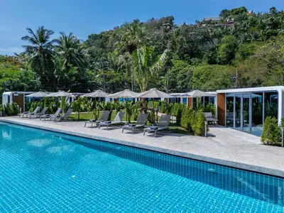 a pool at a resort with lounge chairs and umbrellas at Apple House Phuket a cozy home terrace &pool&beach in Ban Lum Fuang