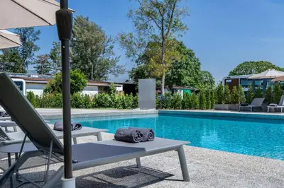 a pool with a lounge chair and an umbrella next to a swimming pool at Apple House with pool&breakfast Steps from the Sea in Ban Lum Fuang