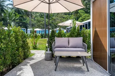 a chair and an umbrella on a patio at Apple House with pool&breakfast Steps from the Sea in Ban Lum Fuang
