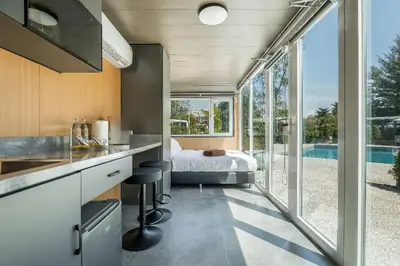 a kitchen and bedroom with a bed and a large window at Apple House with pool&breakfast Steps from the Sea in Ban Lum Fuang